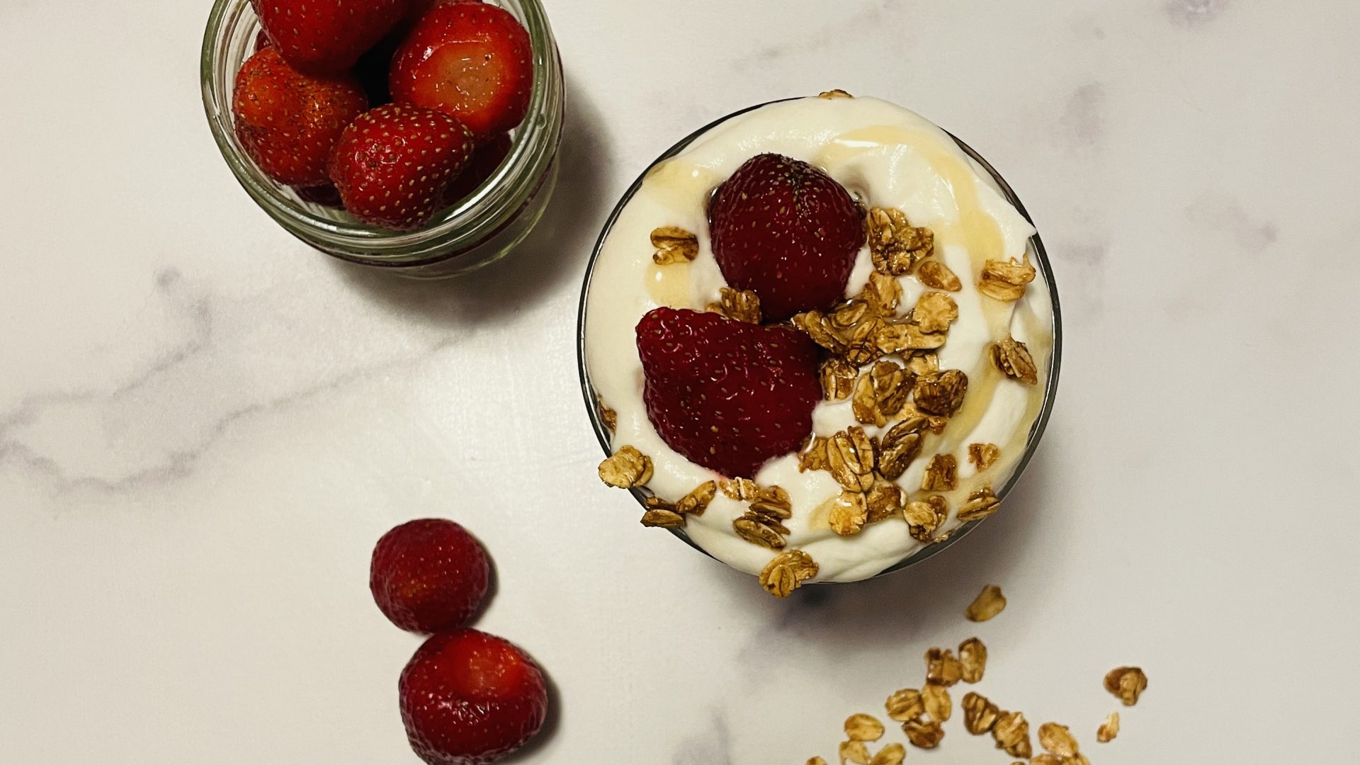 Overhead view of a glass filled with layers of strawberries and whipped cream.