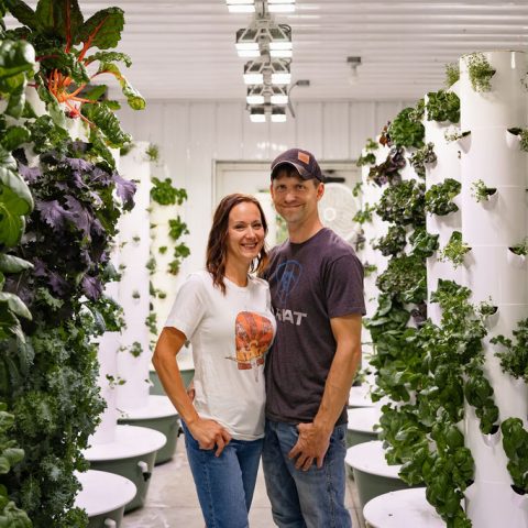 A woman and man smiling in the center of the 2 columns of pillars.