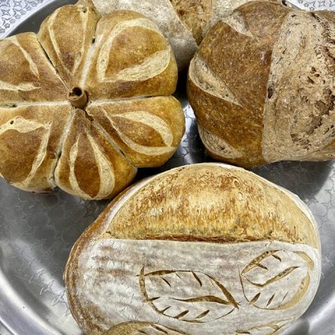 Picture of three loaves of bread. One is shaped like a pumpkin and the other two have artisan designs.