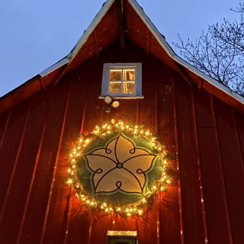 A picture of a holiday light decoration on a red barn.