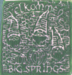 Arial view of a corn maze with gnomes carved into it and the text "Velkommen Big Springs."