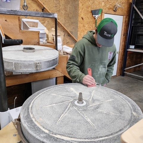 a young man cleans the mill stone