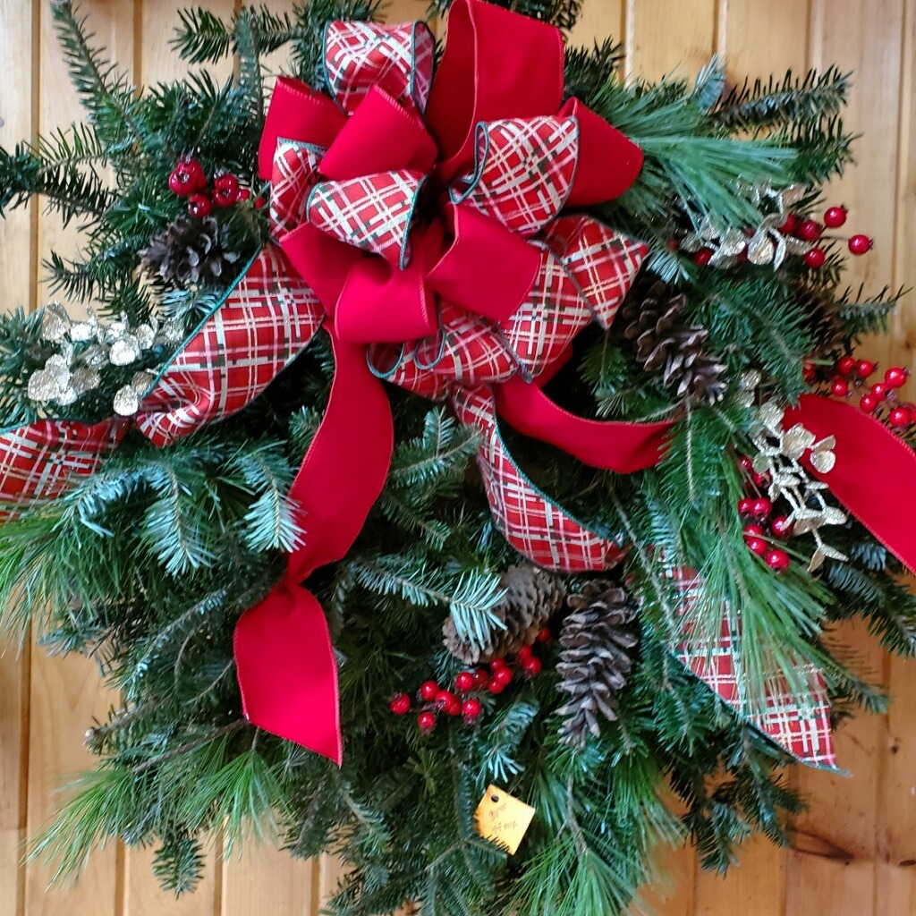 A Christmas wreath with red and plaid ribbons.