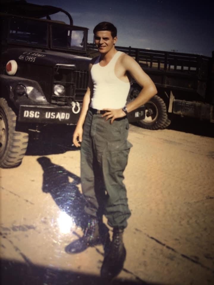 A man in casual military uniform standing with a jeep.