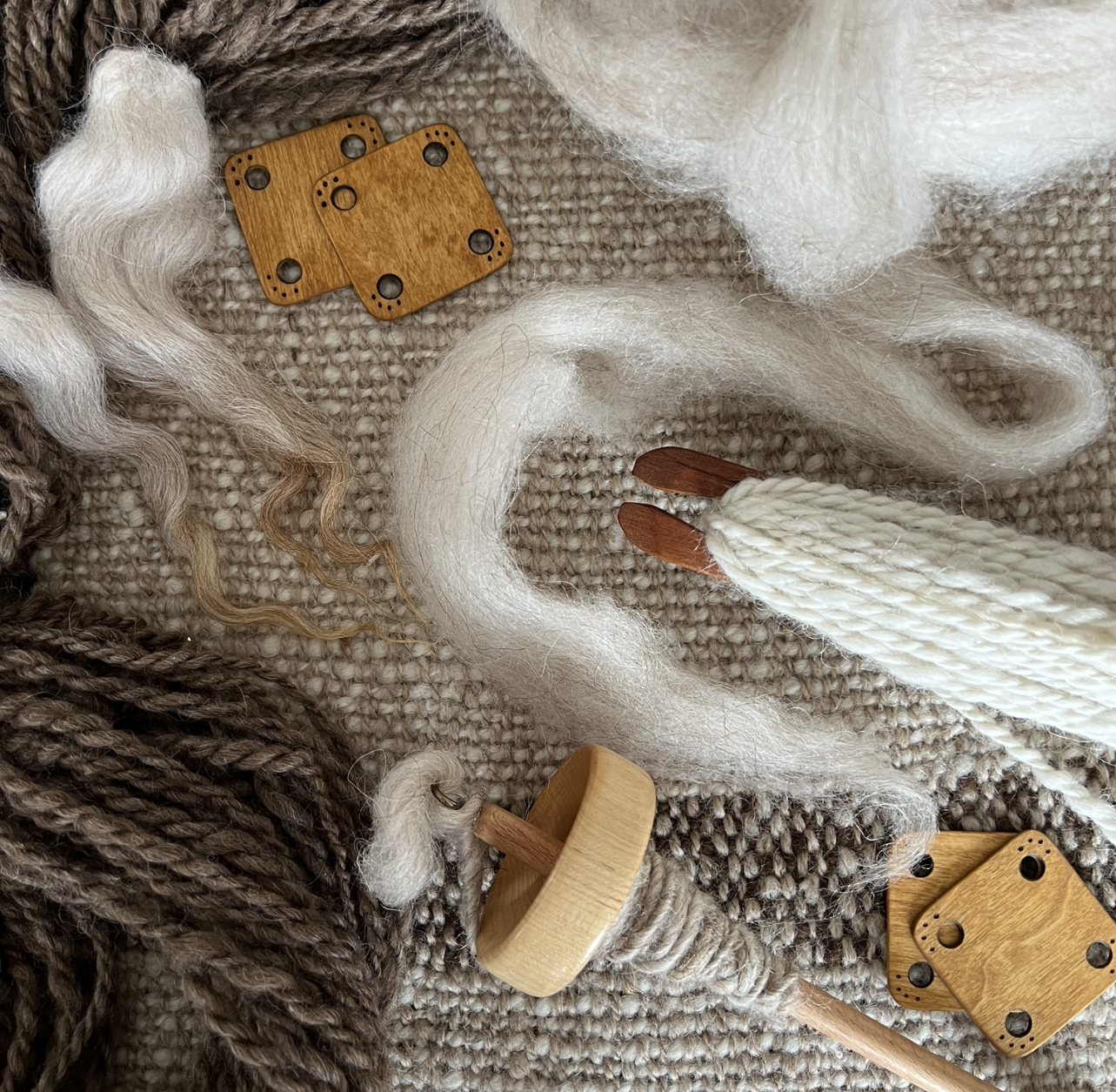 A picture of white and gray wool yarn cat toys and fibers.