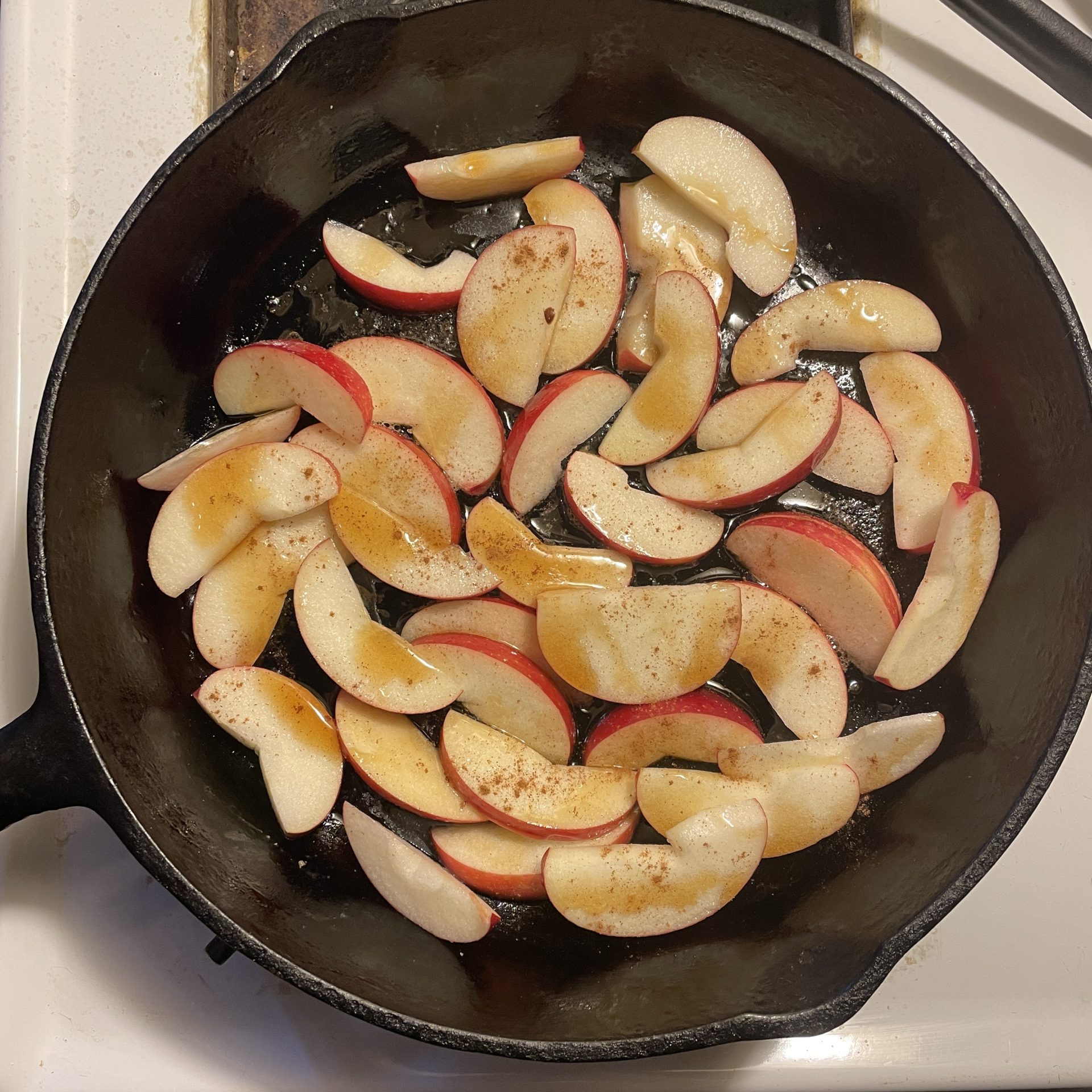 Sliced apples with cinnamon in a cast iron pan.