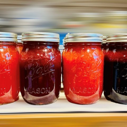 A picture of four jars of jelly or jam in various shades of red/pink.