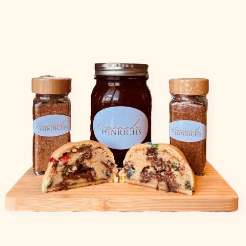 A picture of two bottles of spices, a jar of dark red jelly or jam, and a thick, cookie cut in half with melted chocolate inside.