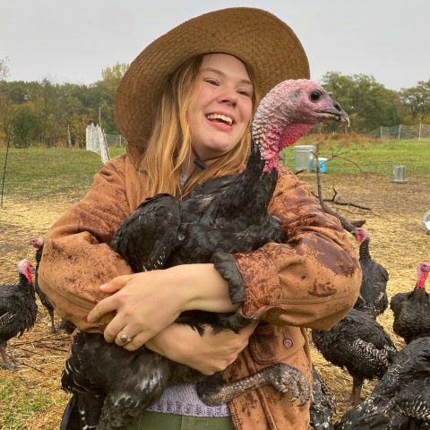 woman with hat smiles and holds turkey