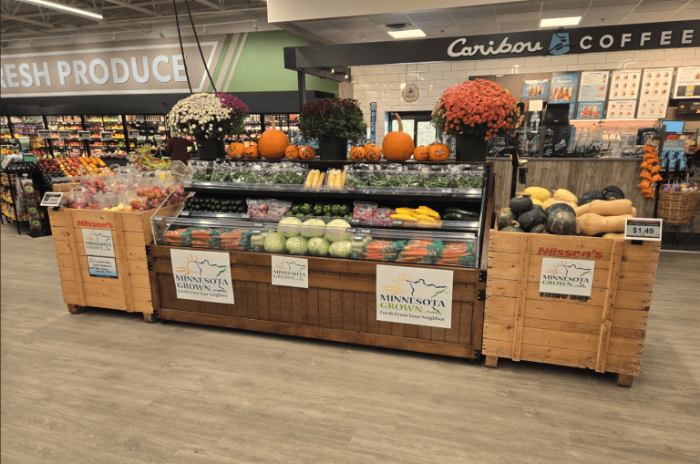 grocery store display featuring mums, squash, carrots, and signs that read Minnesota Grown