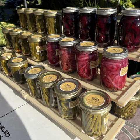 jars of pickles and canned goods in a line on a market table