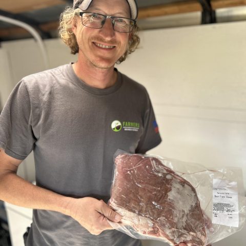 a man smiled and holds a package of raw meat
