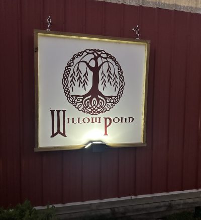 white sign on a red barn that reads Willow Pond