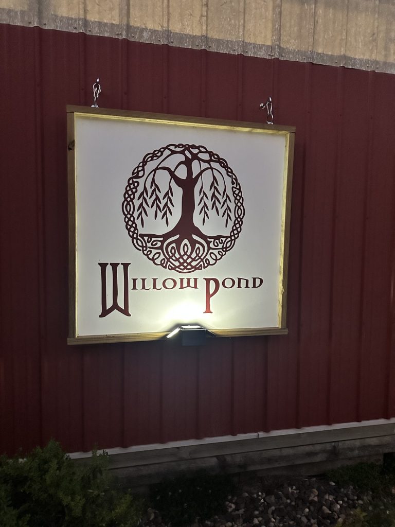 white sign on a red barn that reads Willow Pond