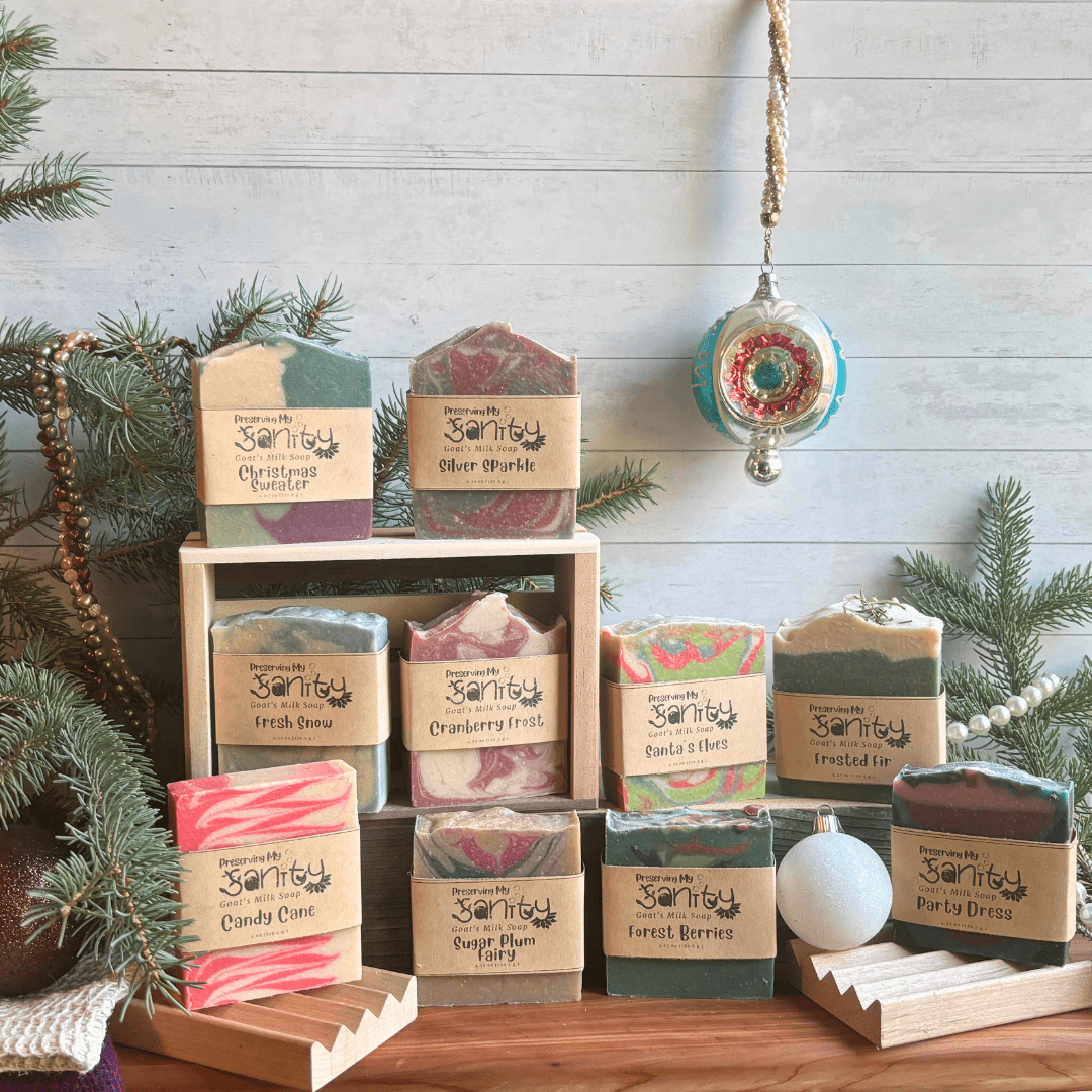 a collection of multicolors soaps displayed on a holiday set up, wooden crates add height and greenery in the background adds color