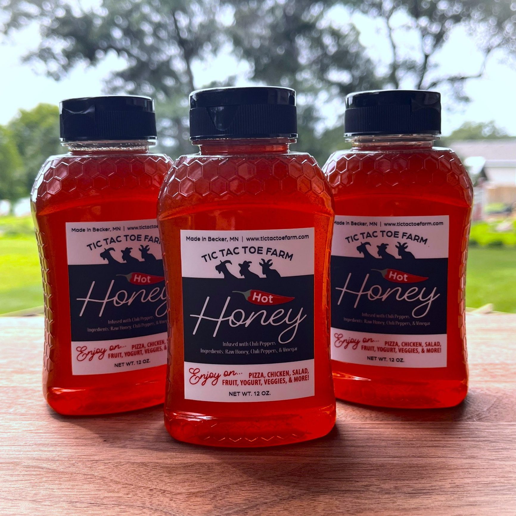 three plastic jars of hot honey on a wooden table