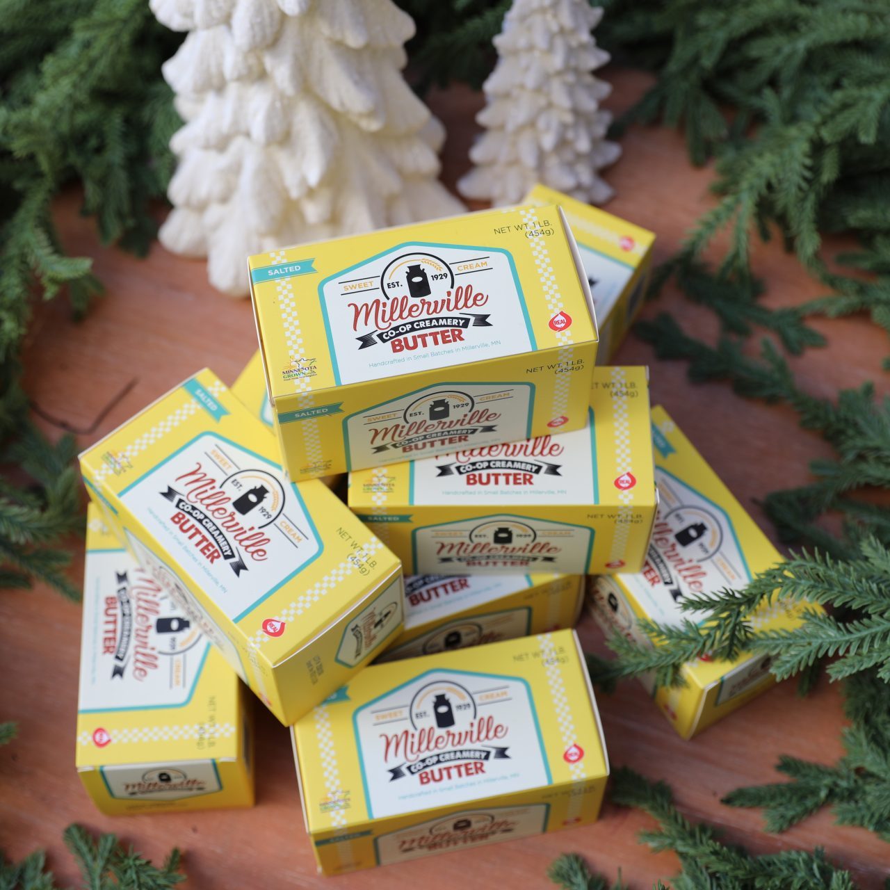 10 pounds of butter surrounded by green boughs and white ceramic christmas tree décor