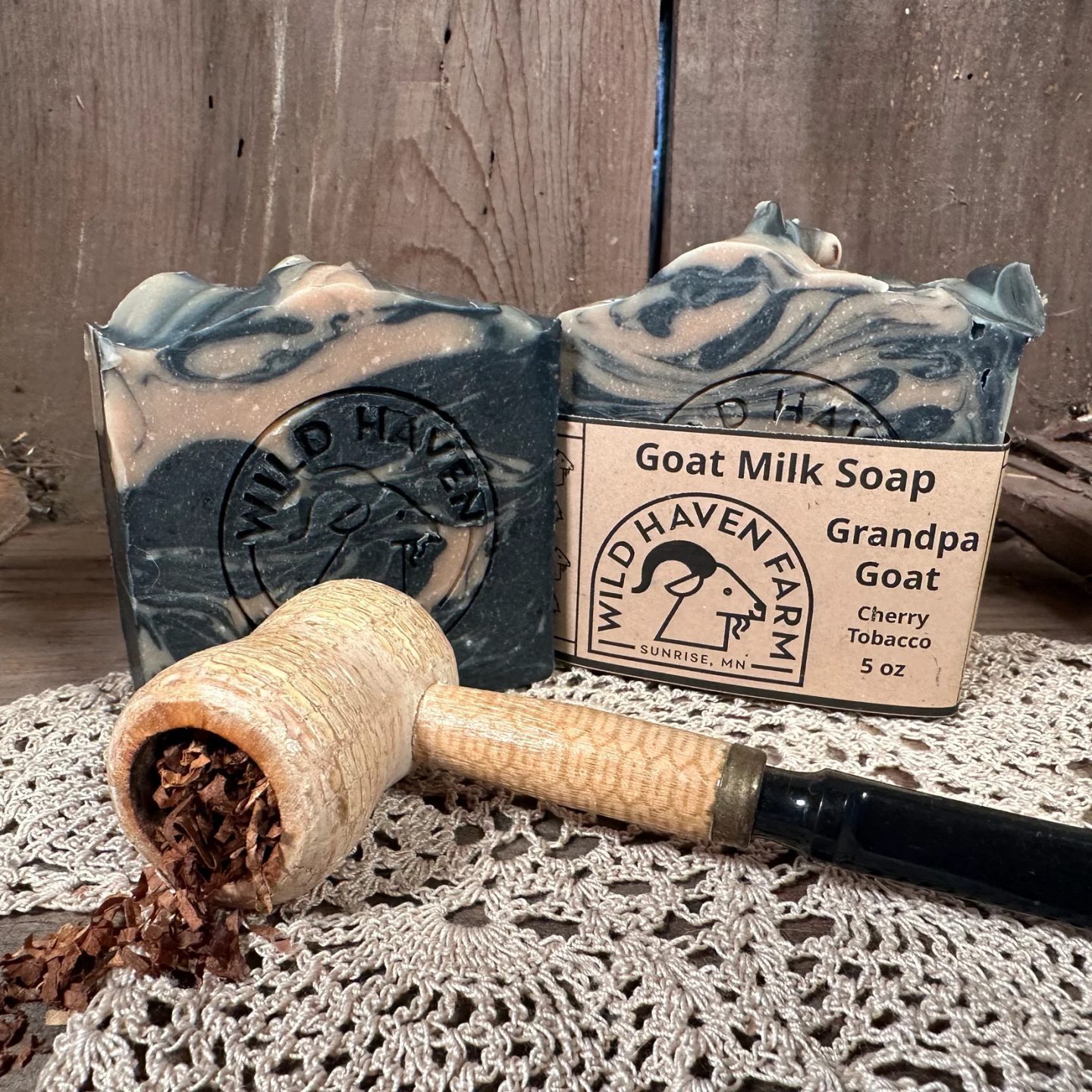 black and cream spirals soap sits behind a corncob pipe willed with loose tobacco all on a white doily