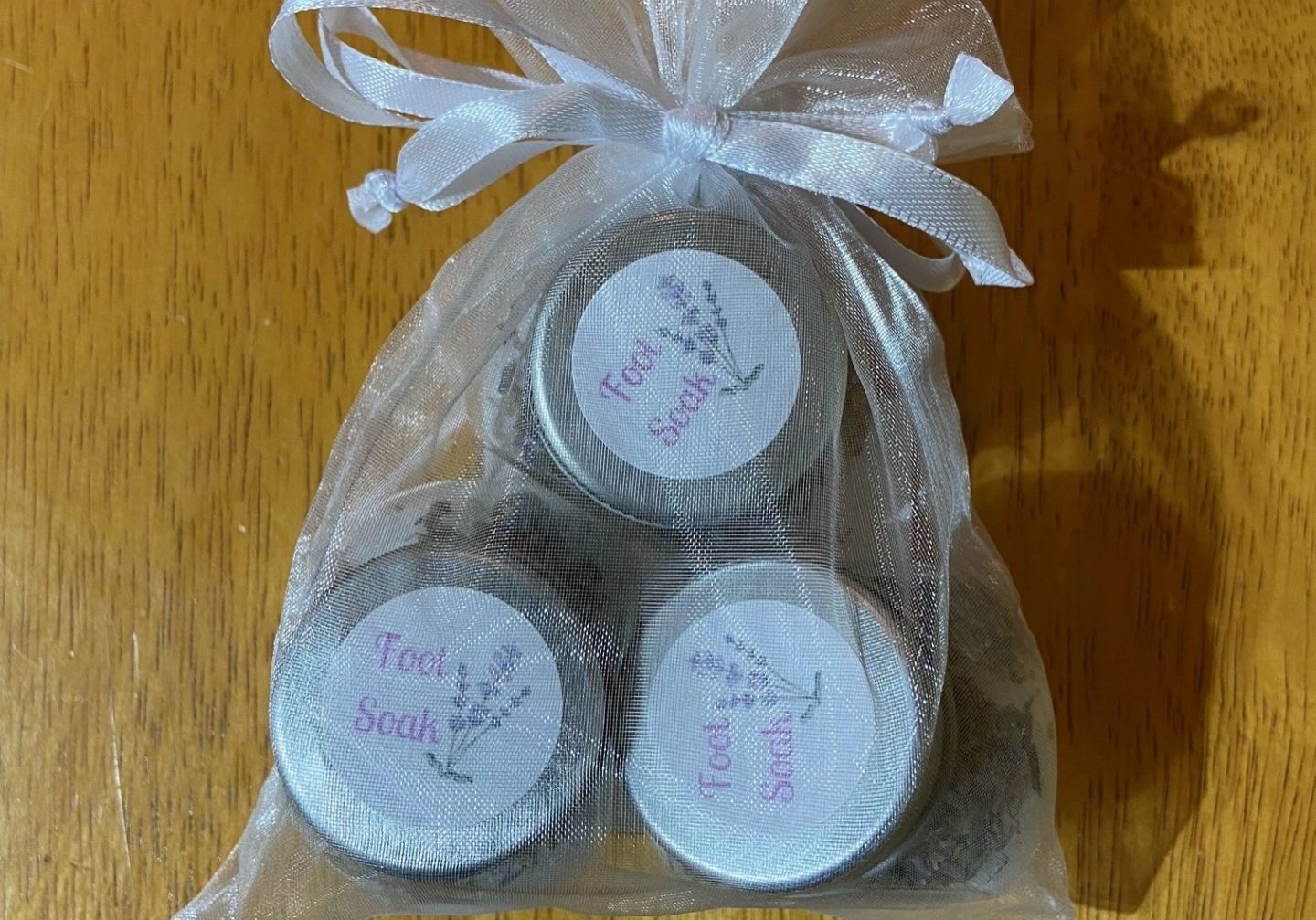 Three small jars of foot soaks inside an organza bag.