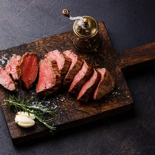 Sliced tenderloin Steak Roast beef on wooden cutting board on dark background