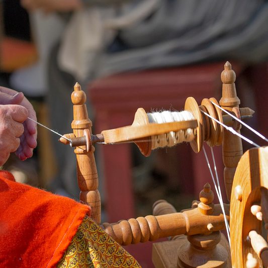 Female artisan spins yarn on an old-fashioned spinning wheel