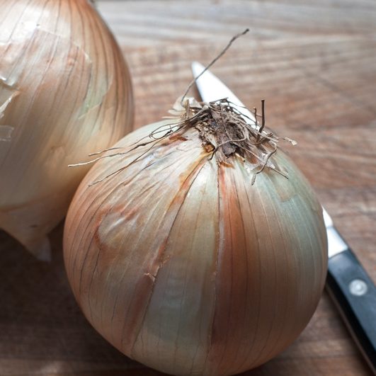 two yellow onions on a cutting board